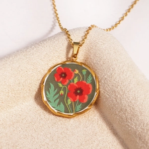 Detail of vintage gold-tone chain necklace with round red poppy flower enamel pendant