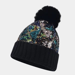 Detailed close-up of colorful sequins and black knit texture on a winter beanie hat
