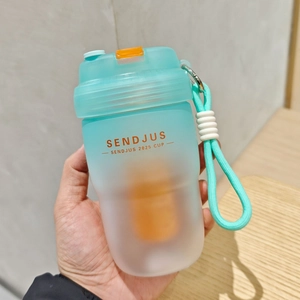 Close-up of hand holding blue and white gradient frosted portable cup with orange strap
