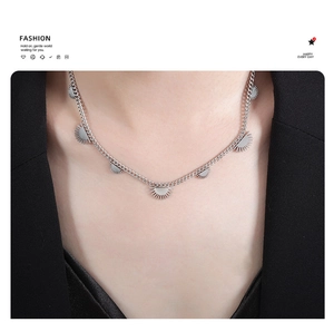 Detailed view of silver curb chain necklace with sun pendants on a black blazer