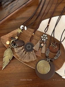 Detailed view of bohemian tassel necklaces with bronze leaf and mandala charms on wood