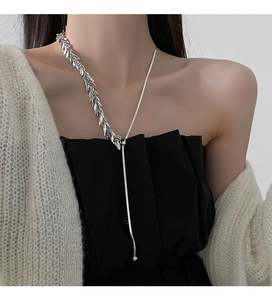 Detail view of silver wheat ear Y-necklace with metallic sequins on a fashion model
