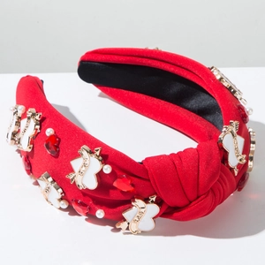Détail d'un serre-tête rouge avec boucle LOVE, pierres précieuses et perles blanches