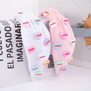 Pink and white plush knotted headband with colorful 3D heart charms and XOXO text