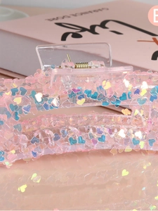 Macro view of a pink hair claw clip with laser heart sequins and a gold metal spring