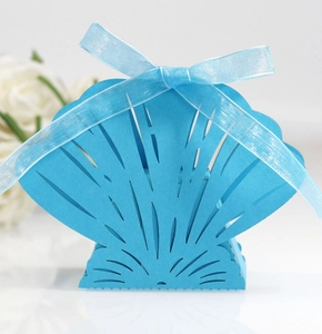 Macro view of laser-cut shell shaped candy box with elegant light blue ribbon bow