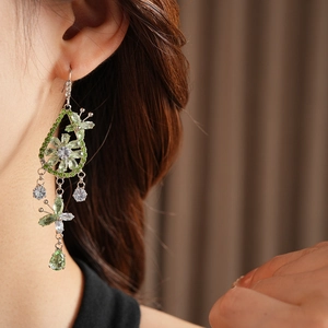 Detail view of long silver tassel earrings with green zircon flower and teardrop charms