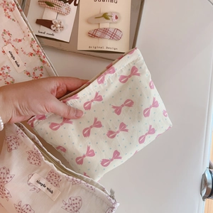 Detail of a pink bow patterned fabric makeup bag featuring a simple wish cloth label