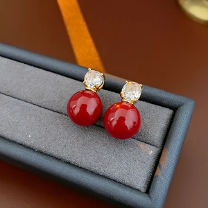 Détail de boucles d'oreilles perles rouges avec zircons dans un écrin en velours