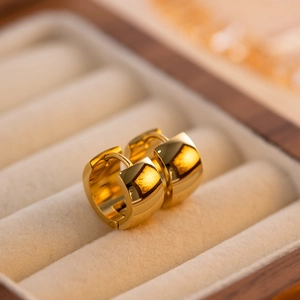 Macro shot of 18K gold plated thick huggie earrings on premium beige velvet