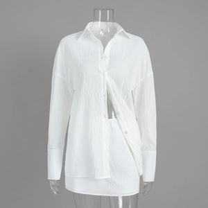 Detail of white two-piece set showing pleated fabric texture on shirt and skirt