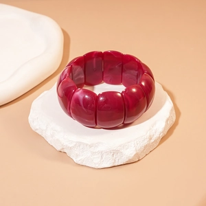 Macro detail of dark red marbled acrylic geometric bracelet on white stone tray