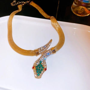 Detailed macro view of a gold mesh necklace featuring a snake pendant with green crystals