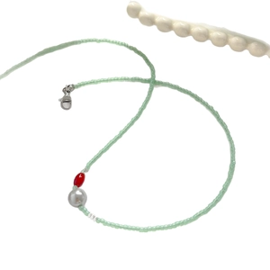 Collier de perles fraîches avec agate rouge et perles vertes sur fond blanc