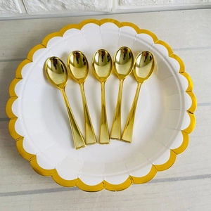 Close-up of golden 9.8cm disposable dessert spoons on a decorative gold-rimmed plate