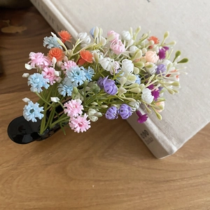 Detail of colorful acrylic floral hair clip featuring multi-color mini blossoms on a book