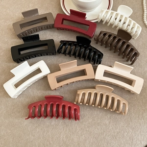 Flat lay of diverse geometric hair claws in earth tones with elegant lifestyle props