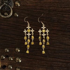 Macro shot of vintage gold tassel earrings with teardrop gems on a retro wood background