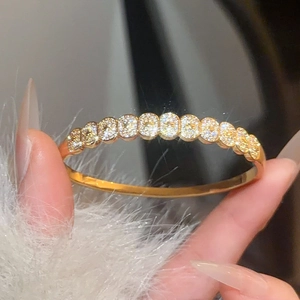 Detail of gold plated bangle featuring micro-pave set oval cubic zirconia stones