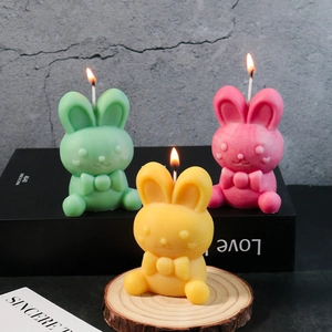 Detailed view of burning rabbit candles in pink, green, and yellow with bow ties