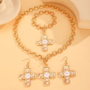 Detailed view of vintage gold cross jewelry set with white pearls and textured finish