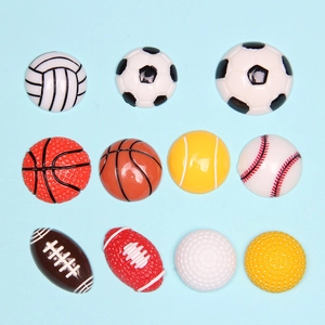 Flat lay of 12 resin sports ball charms including basketball and soccer for DIY crafts