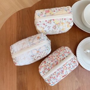 Floral quilted cotton makeup bags in yellow, purple and red-blue patterns on a wooden table