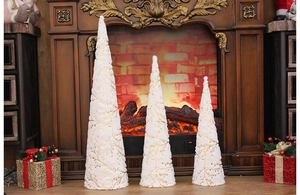 Tre alberi a cono in peluche crema con filo dorato su un caminetto accogliente