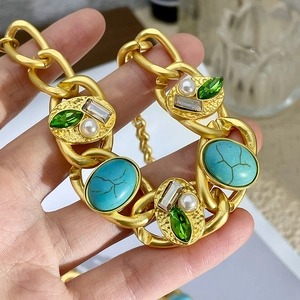 Detailed macro view of vintage gold chain necklace with turquoise stones and green crystals