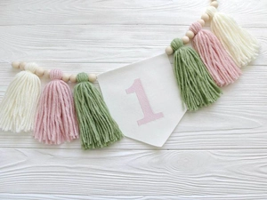 Detail of high chair banner with number 1, colorful tassels, and wooden beads