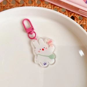 Macro detail of a cute acrylic bunny keychain with pink clasp on a clean white plate