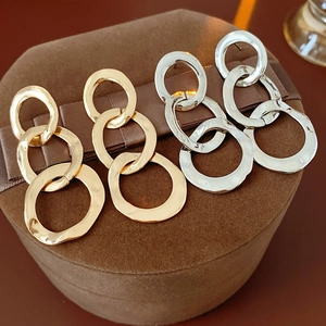 Detailed close-up of gold and silver textured triple-link drop earrings on a velvet box