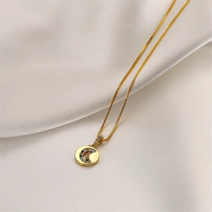 Collana con ciondolo a luna dorata e zirconi colorati su raso bianco lucido