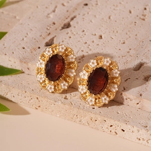 Macro shot of retro oval earrings with golden metal, white flowers and amber gemstones