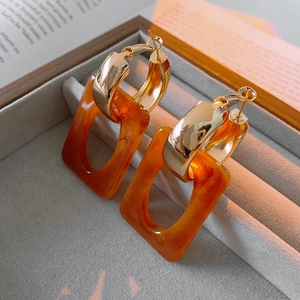 Detail of vintage rectangular earrings with amber resin pendant and golden metal hoop