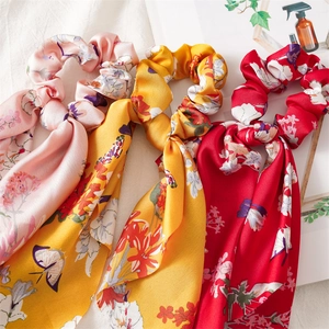 Three floral satin scrunchies with streamers in pink, yellow and red colors