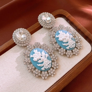 Vue détaillée des boucles d'oreilles style camée vintage avec relief floral et strass