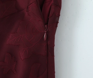 Detailansicht eines tiefroten Jacquard-Kleides mit Blumenmuster und verdecktem Reißverschluss