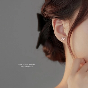 Macro view of S999 silver bow stud earring with screw back on woman's earlobe