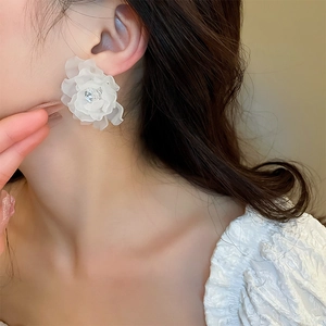 Details von eleganten weißen Acrylblumen-Ohrringen mit Kristallmitte am Model