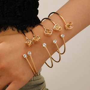 Détail de bracelets dorés avec breloques cygne et cœur et pierres de projection