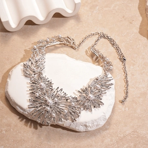 Detailed shot of silver metallic flower necklace with pearls on white display stone