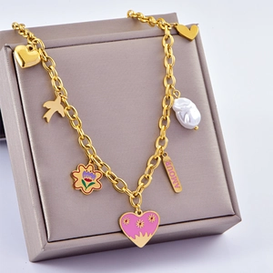 Close-up of golden multi-charm necklace with Amour bar, pearl and pink enamel heart