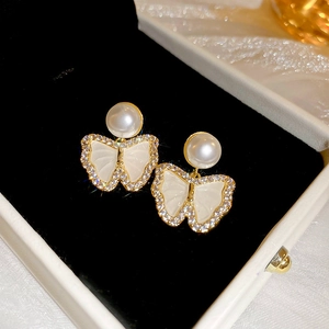 Detailed view of gold butterfly stud earrings with small pearls and crystals inlay