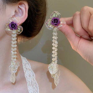 Detail view of long tassel flower earrings with purple rose and acrylic petals on a model