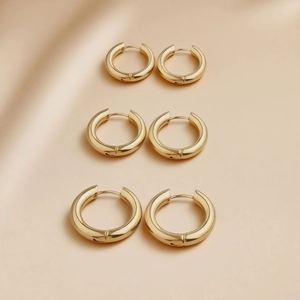 Polished gold titanium steel hoop earrings set in three sizes on silk background