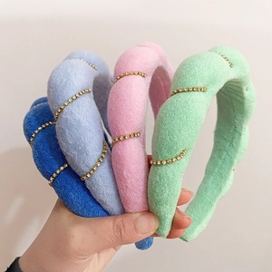 Close-up of plush velvet headbands in blue, pink and green with rhinestone gold stripes