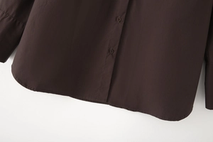 Detail of dark brown poplin shirt showing fine stitching and smooth fabric texture