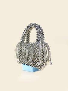 Macro shot of silver beaded woven handbag featuring metallic fringe detail and structured shape