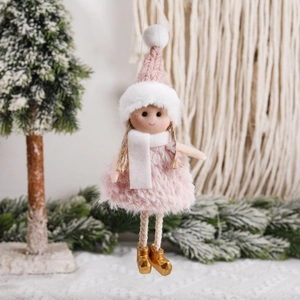 Pink and white Christmas angel doll ornament hanging on a pine tree with cozy winter background
